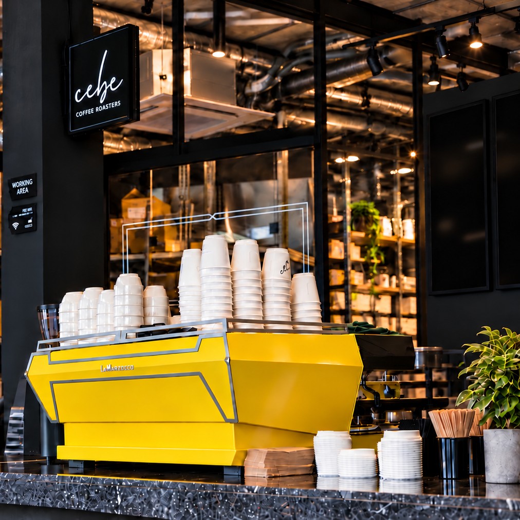 CEBE Boxhagener Straße 82, home of our roastery: the bar with a yellow La Marzocco espresso machine.